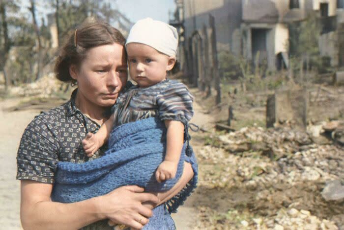 Польская женщина с маленьким ребенком на руках стоит на улице Варшавы